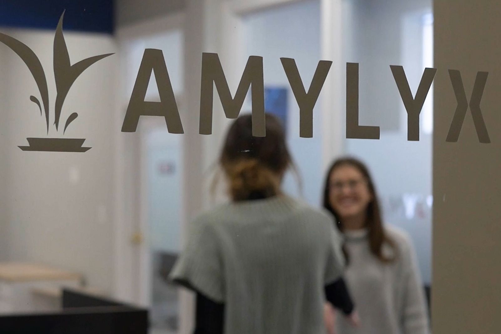 The logo of Amylyx Pharmaceuticals is seen through an office window.