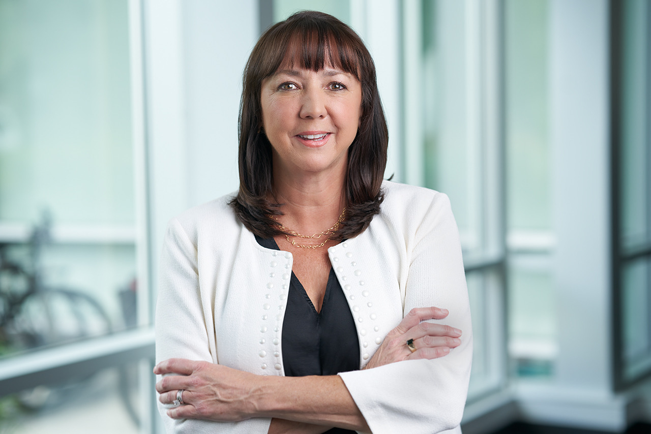 A woman in business attire stands outside a conference room