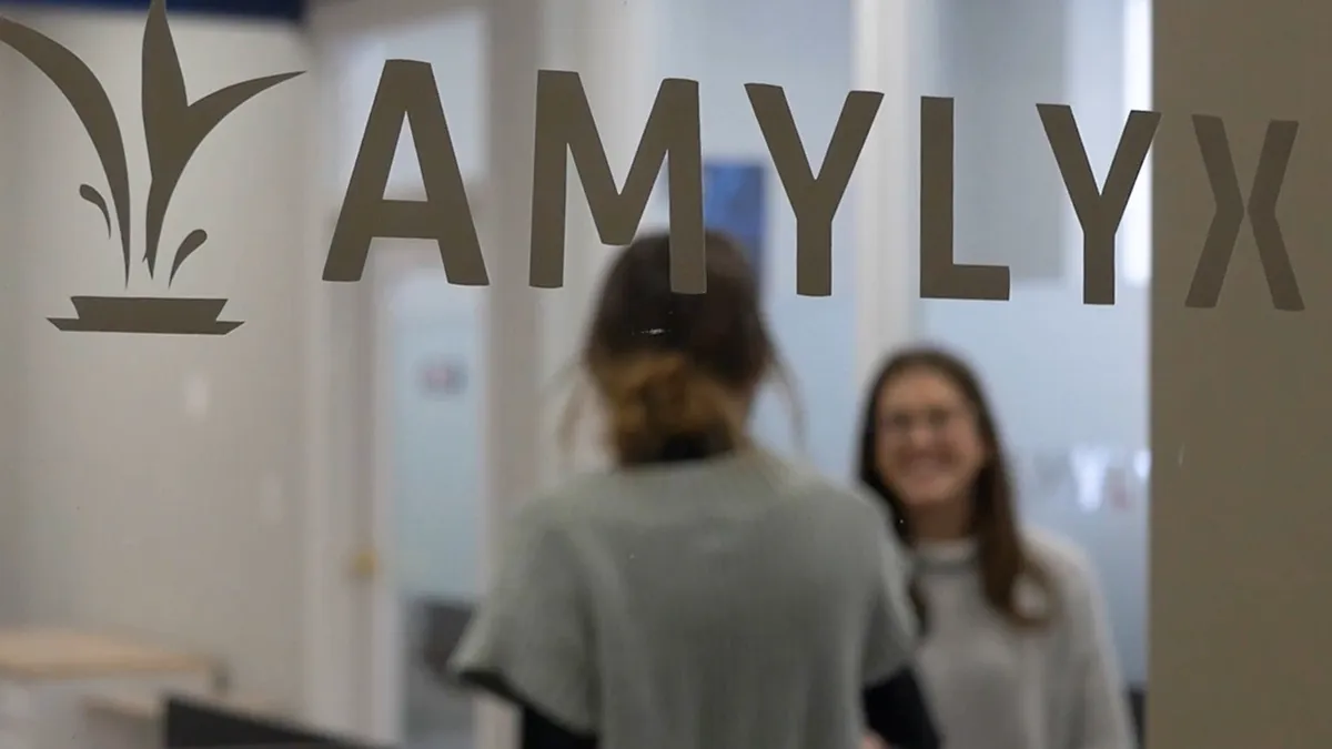 The logo of Amylyx Pharmaceuticals is seen through an office window.