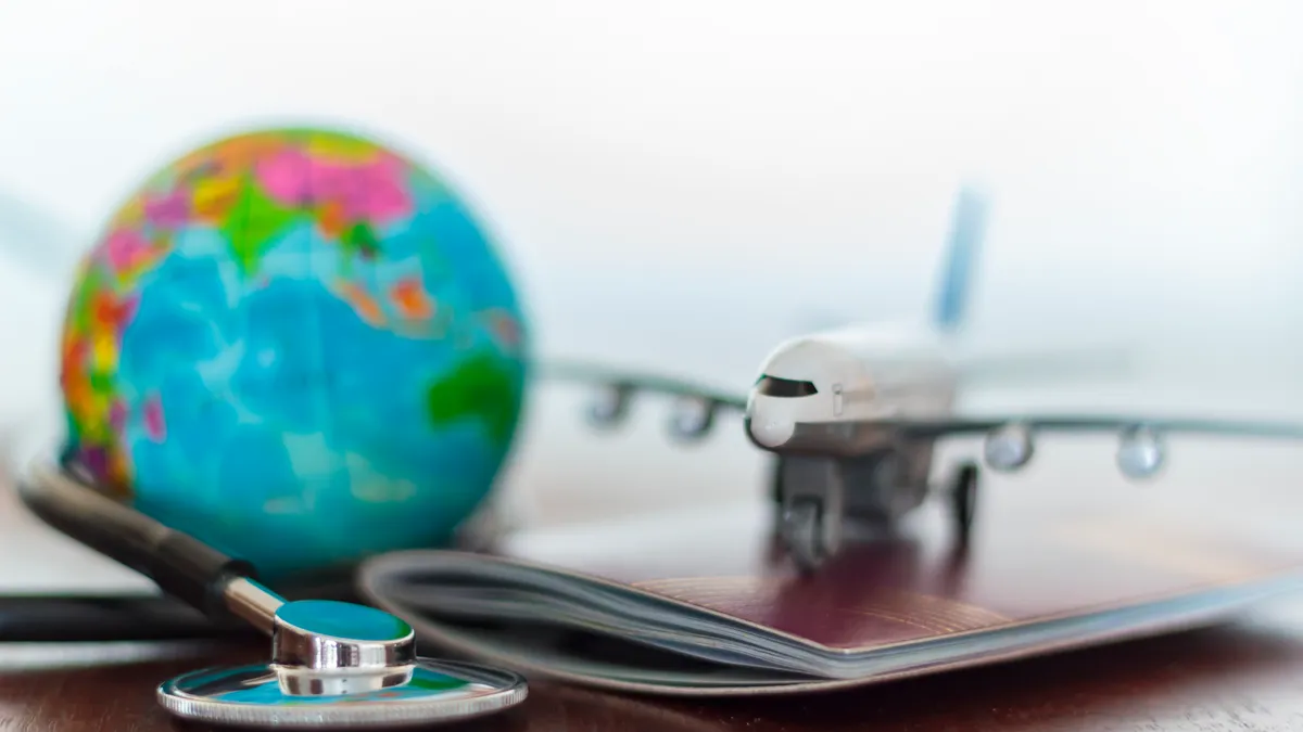 Stethoscope , passport document, airplane and globe on a table.