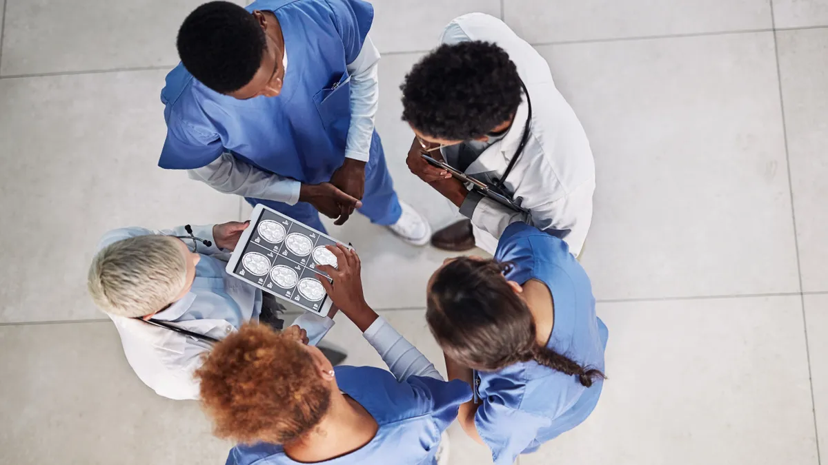 High angle shot of a group of medical practitioners analyzing x-rays on a digital tablet in a hospital.