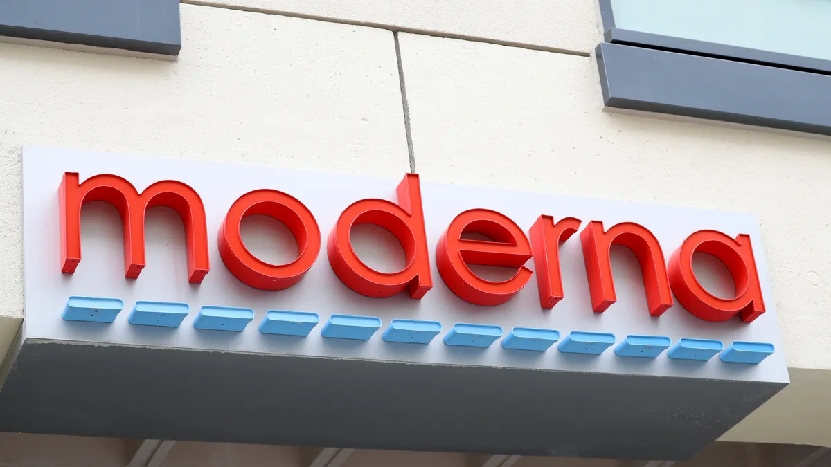 A red Moderna sign hangs on the front of a beige building.