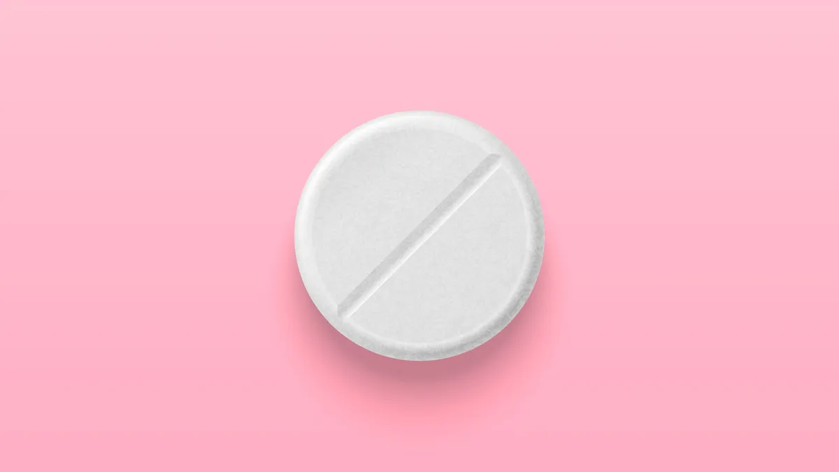 White medical pill isolated on pink background