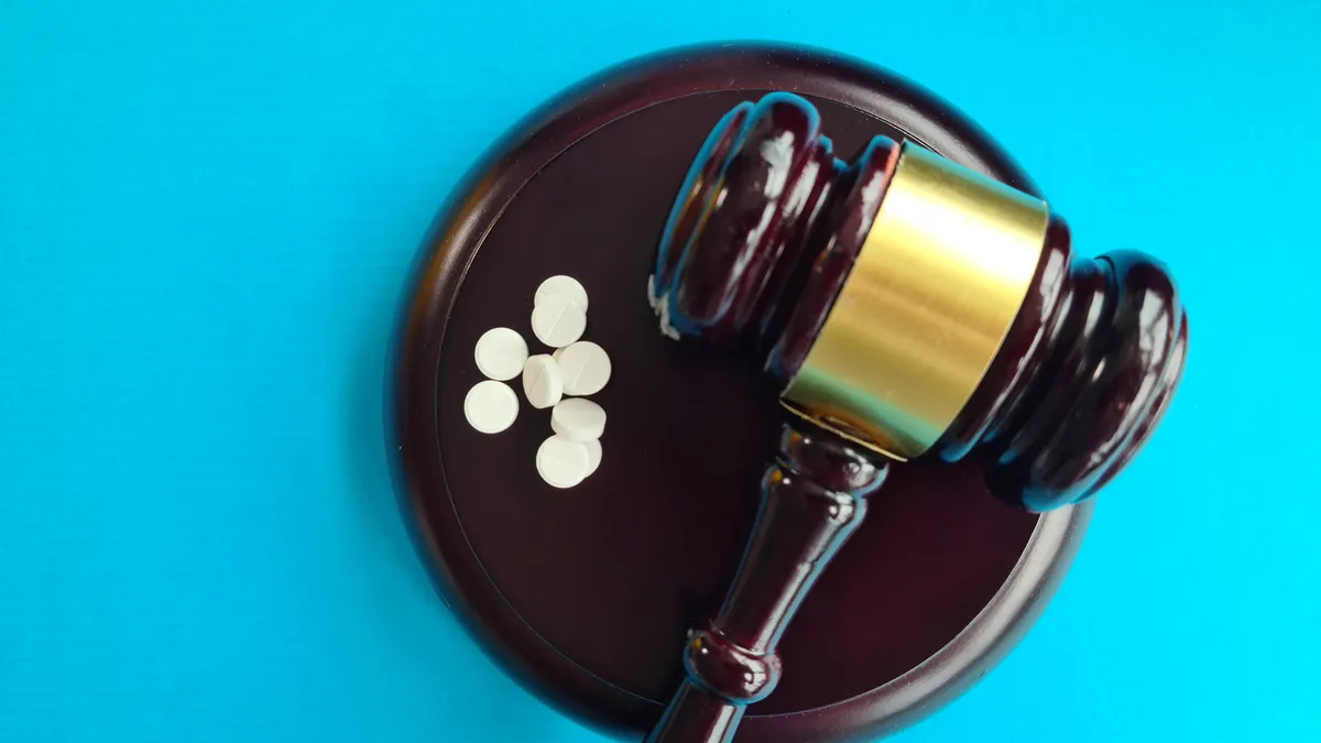 Judge gavel and pills against blue backdrop