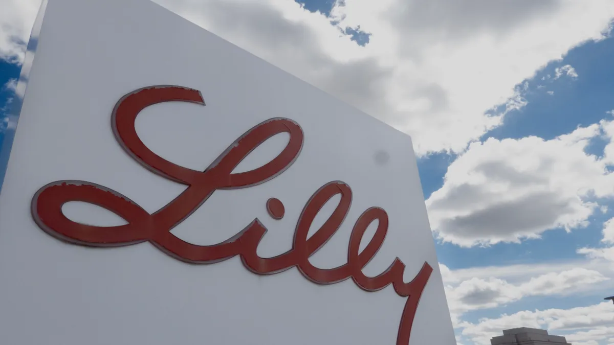 A white sign with the word Lilly written in red stands outside of an office.