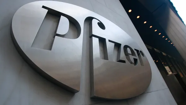 A chromatic Pfizer sign hangs on a building façade