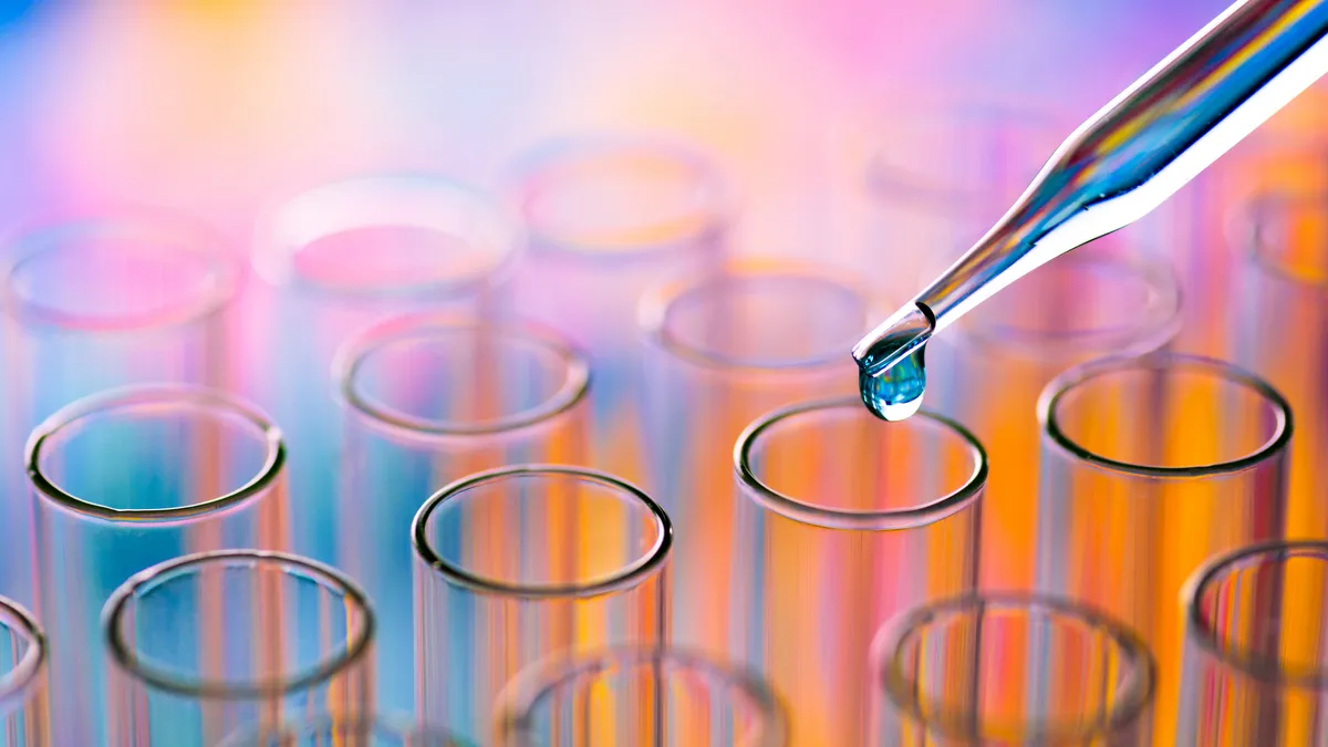 Close-Up Of Pipette Dripping Chemical In Test Tube At Laboratory