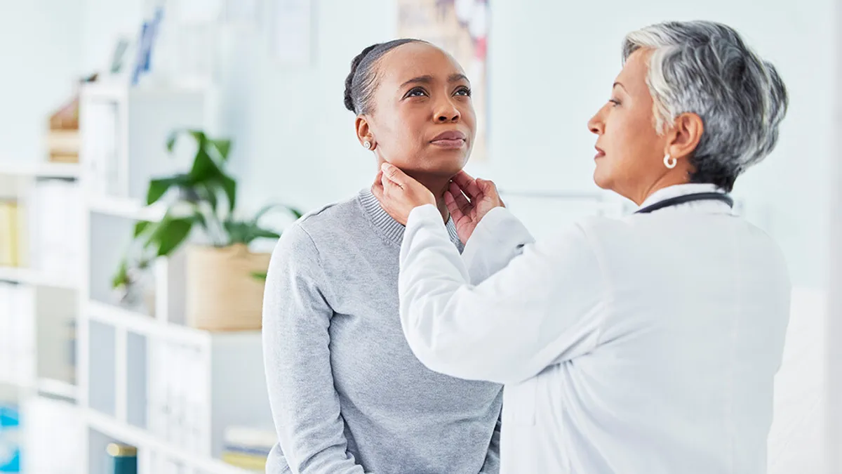 Doctor checking patient's lymph nodes under their jaw in a medical office.